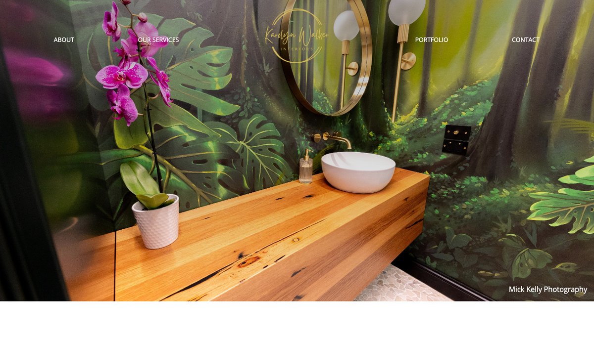 Karolyn Walker Interiors homepage showing a custom vanity with a botanical mural wall, brass fittings and timber bench